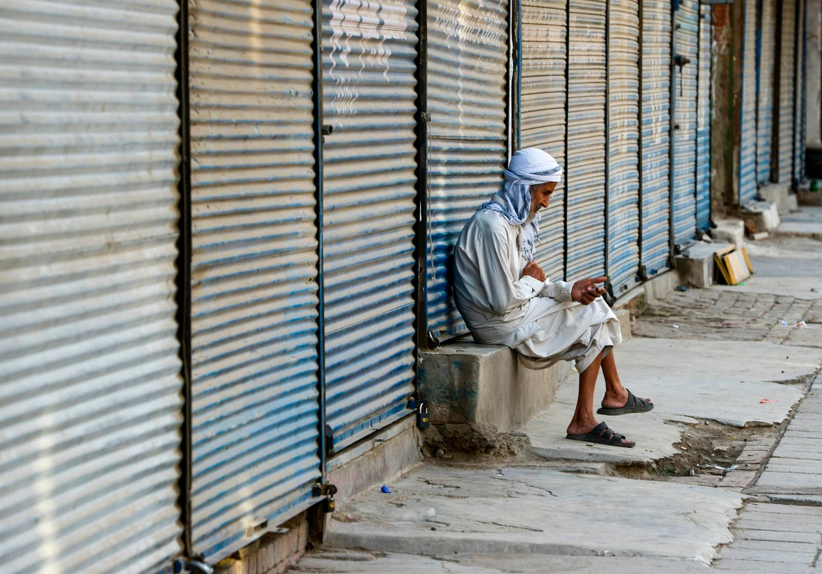 A Pakistani elderly man sits at a shuttered market during a traders countrywide strike against the prices hike, in Peshawar on July 13, 2019. (AFP)