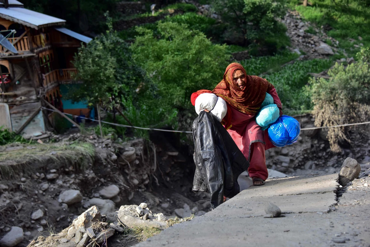 In this picture taken on July 17, 2019, a Pakistani Kashmiri flood-affected victim holds her belongings near her damaged house in Laswa Valley, near the Line of Control in Pakistan-administered Kashmir. (AFP)