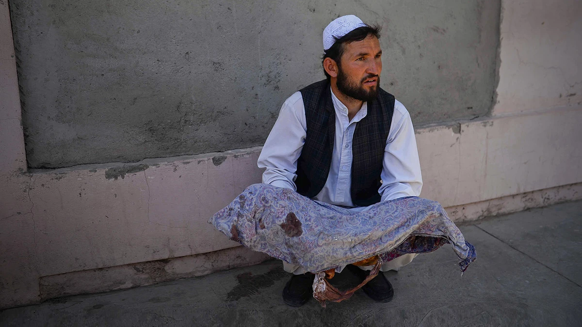 An Afghan man holds the dead body of a child killed when a bus hit a roadside bomb on the Kandahar-Herat highway, at a hospital in Herat on July 31, 2019. (AFP)