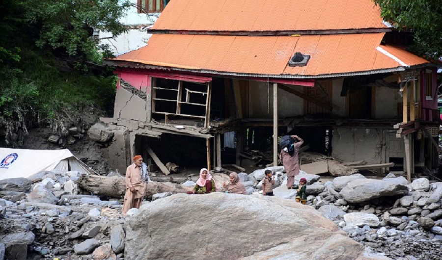 Flood-affected victims in Azad Kashmir standing near the damaged house. (AFP)