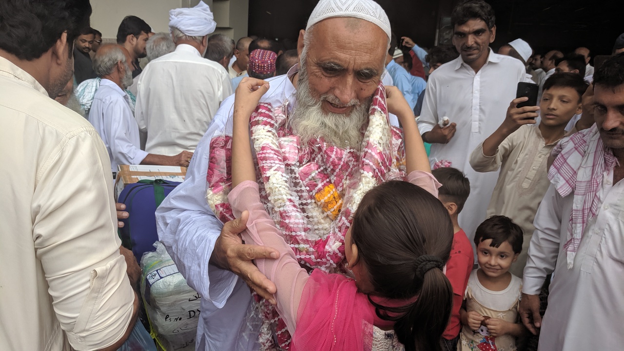 A girl drapes a garland around the neck of her grandfather as he returns to Pakistan after performing the Hajj, at Karachi's Jinnah International Airport on Thursday, August 22, 2019. (AN Photo)
