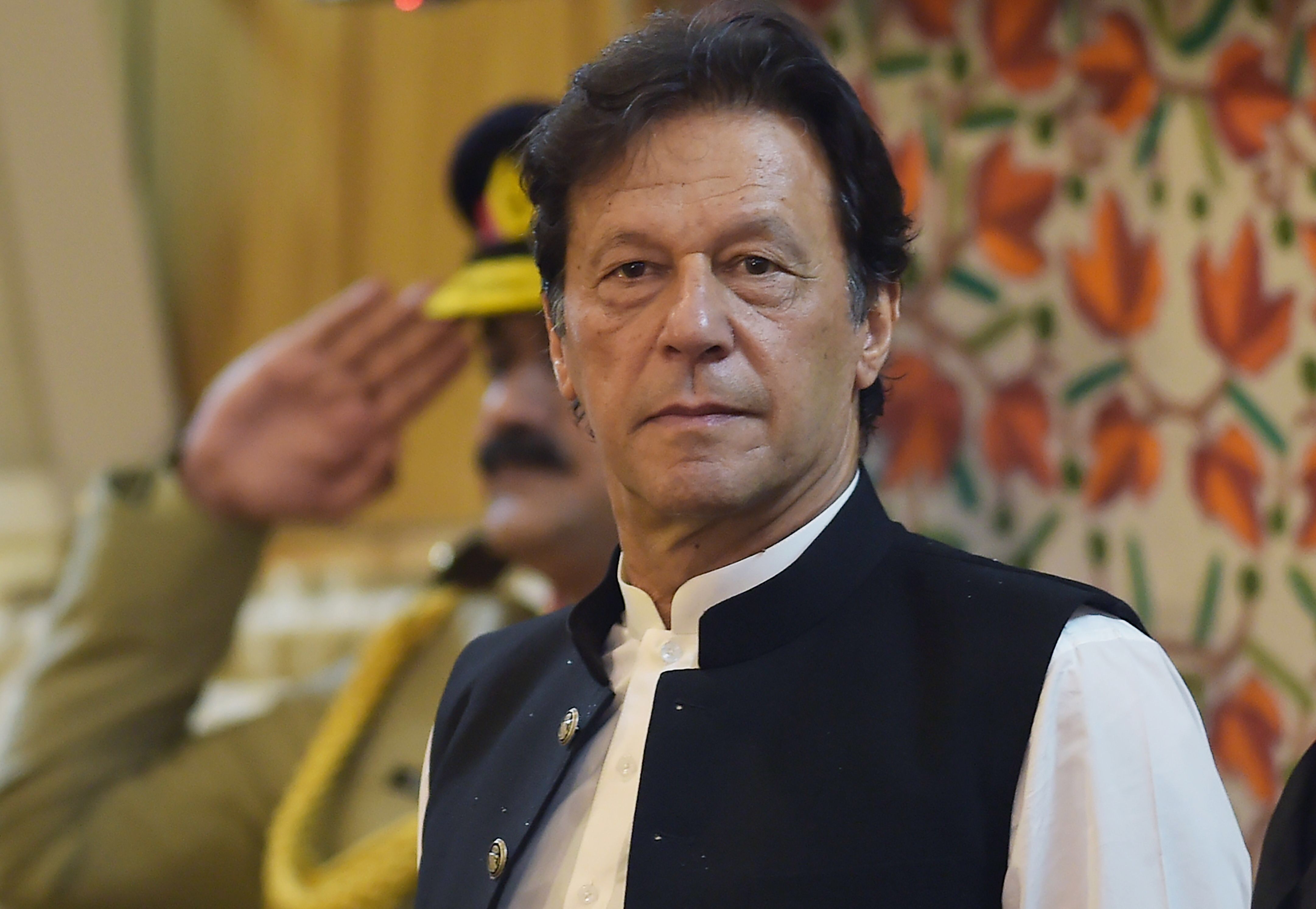 In this file photo taken on August 14, 2019, Pakistan's Prime Minister Imran Khan listens to the national anthem as he arrives at the legislative assembly in Muzaffarabad, the capital of Azad Kashmir. Khan called on the country August 29 to join mass demonstrations to protest Delhi's actions in Indian-administered Kashmir as tensions between the nuclear-armed rivals continued to boil. (AFP)