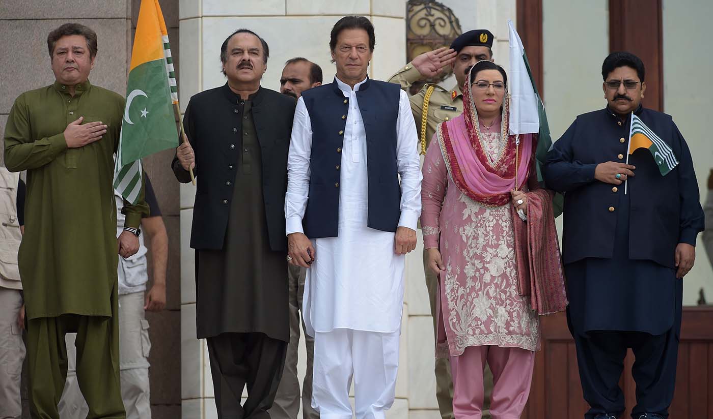 Pakistan's Prime Minister Imran Khan, center, stands with his party leaders as they listen to the national anthem as he arrives to address the nation outside the Prime Minister's Office in Islamabad on August 30, 2019. (AFP)