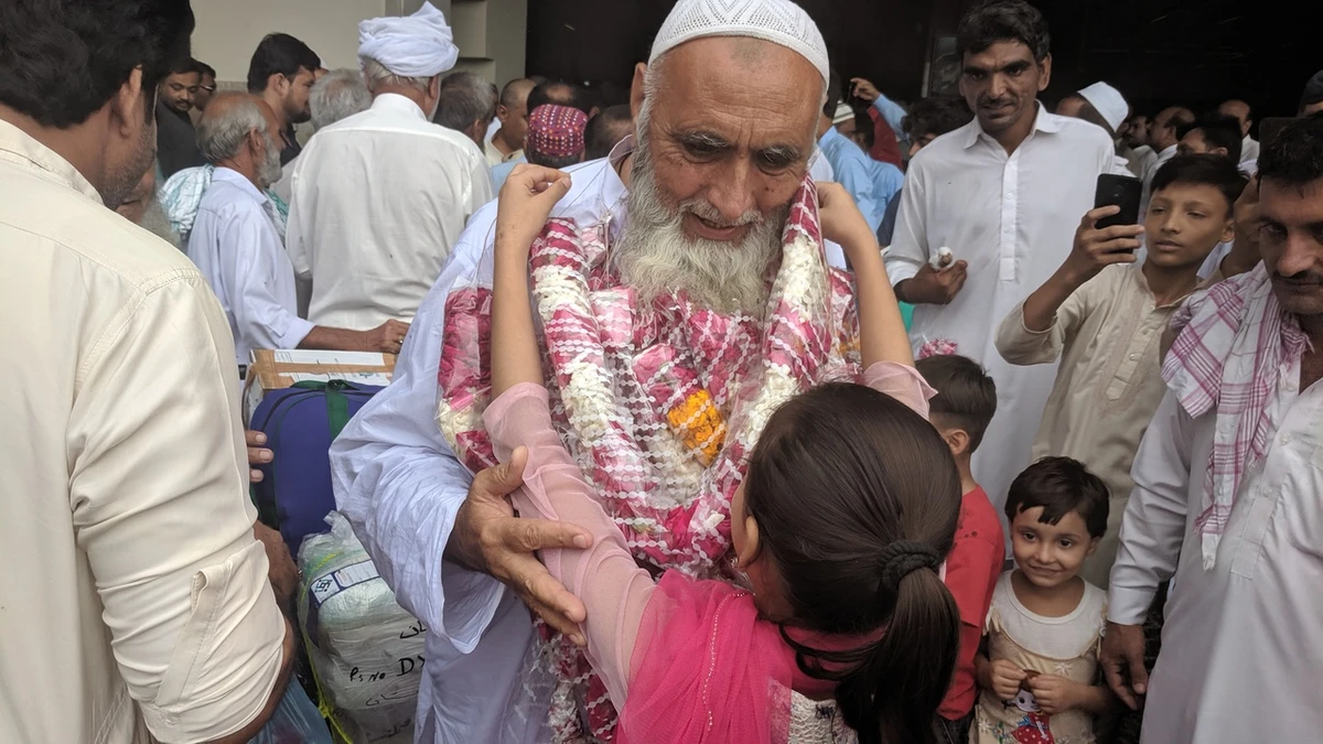 A girl drapes a garland around the neck of her grandfather as he returns to Pakistan after performing the Hajj, at Karachi's Jinnah International Airport on Thursday, August 22, 2019. (AN Photo)