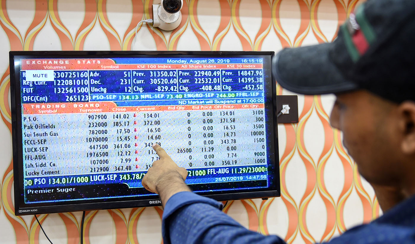 In this file photo, a stockbroker points out the latest share prices on a screen during a trading session at the Pakistan Stock Exchange (PSX) in Karachi on August 26, 2019. (AFP)
