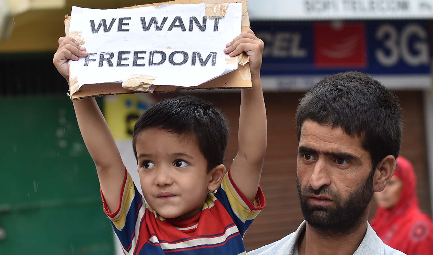 A Kashmiri protester carries his son as he holds a placard during a protest in Srinagar on Aug. 27, 2016 (AFP/File)