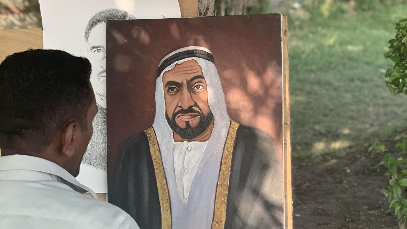 Shoukat Ali sits face to face with his ‘lucky’ portrait of Sheikh Zayed by the side of the main road in Lahore, on Sept. 7, 2019. (AN photo)