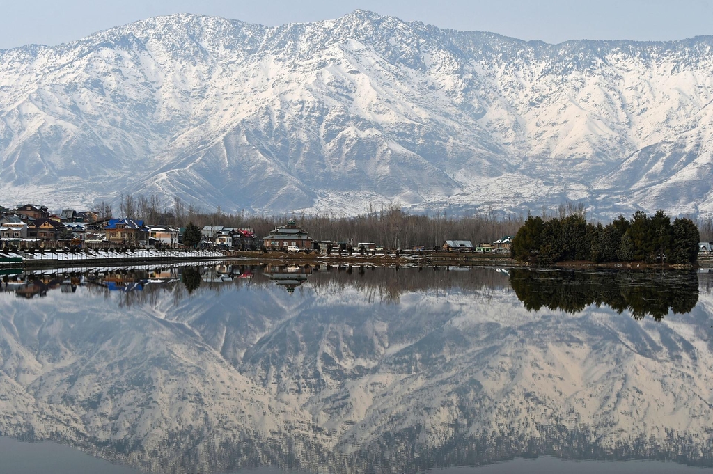 Snow-covered mountains are reflected in Dal Lake in Srinagar, the summer capital of Kashmir. (AFP)