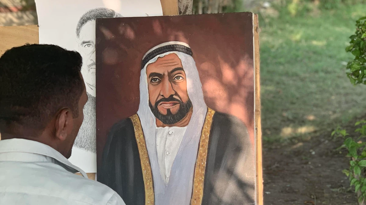 Shoukat Ali sits face to face with his ‘lucky’ portrait of Sheikh Zayed by the side of the main road in Lahore, on Sept. 7, 2019. (AN photo)
