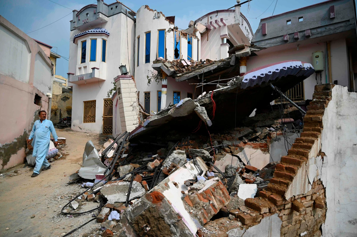 A Pakistani earthquake survivor walks past a collapsed house in an earthquake-hit area on the outskirts of Mirpur in Pakistan-controlled Kashmir on September 25, 2019. Rescuers battled along badly damaged roads and combed through toppled buildings September 25 to reach victims of an earthquake that killed at least 25 people and injured hundreds more in northeast Pakistan. (AFP)