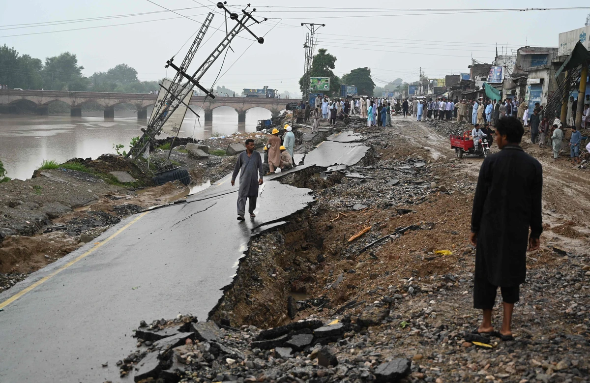 People stand on a damaged road in an earthquake-hit area on the outskirts of Mirpur on September 25, 2019. Rescue workers battled on September 25 to reach people affected by a shallow earthquake that rocked northeast Pakistan a day earlier, killing at least 22 people and injuring hundreds more as it tore roads apart and felled buildings. (AFP)