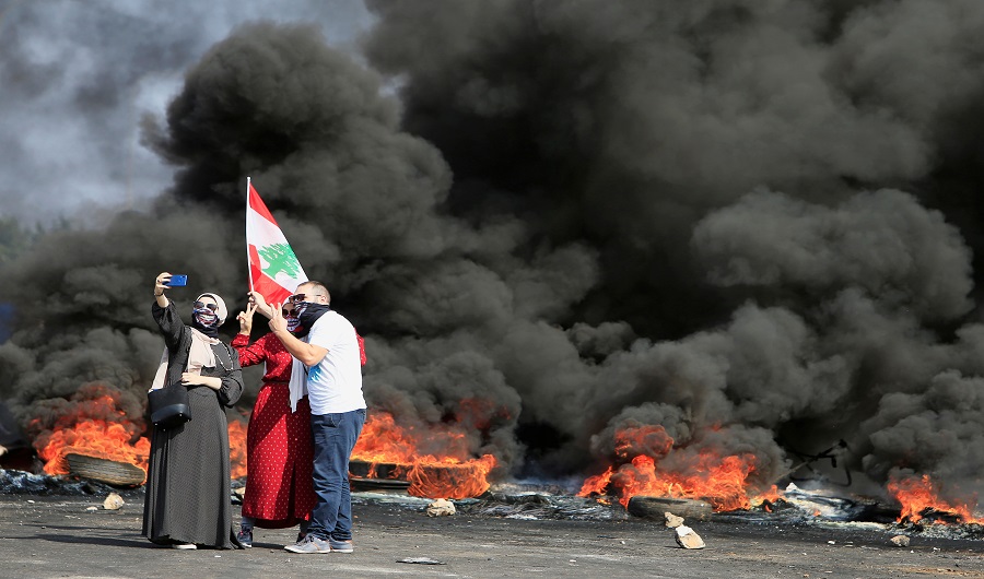 Demonstrators take a selfie in front of burning tires during a protest targeting the government over an economic crisis, at Barja area blocking off a main road leading from southern Lebanon to Beirut, October 18, 2019. (REUTERS photo)