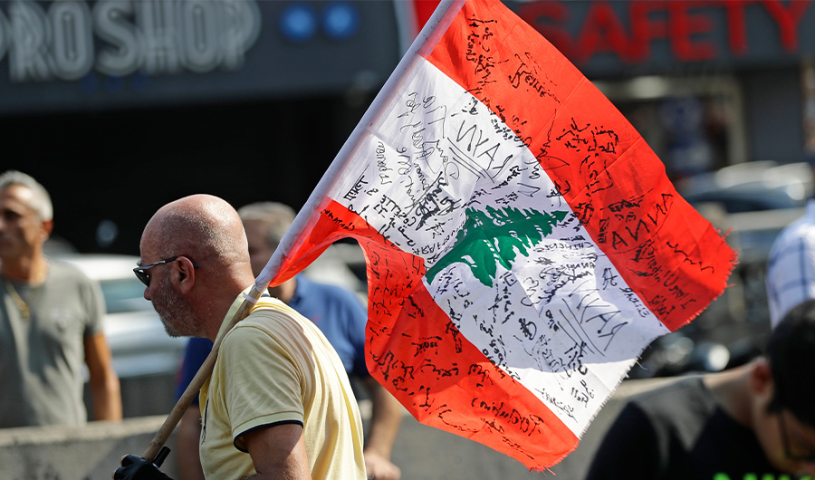 A Lebanese demonstrator carries a national flag bearing signatures of people protesting against corruption in the area Zouk Mosbeh, north of the capital Beirut, on October 21, 2019. (AFP)