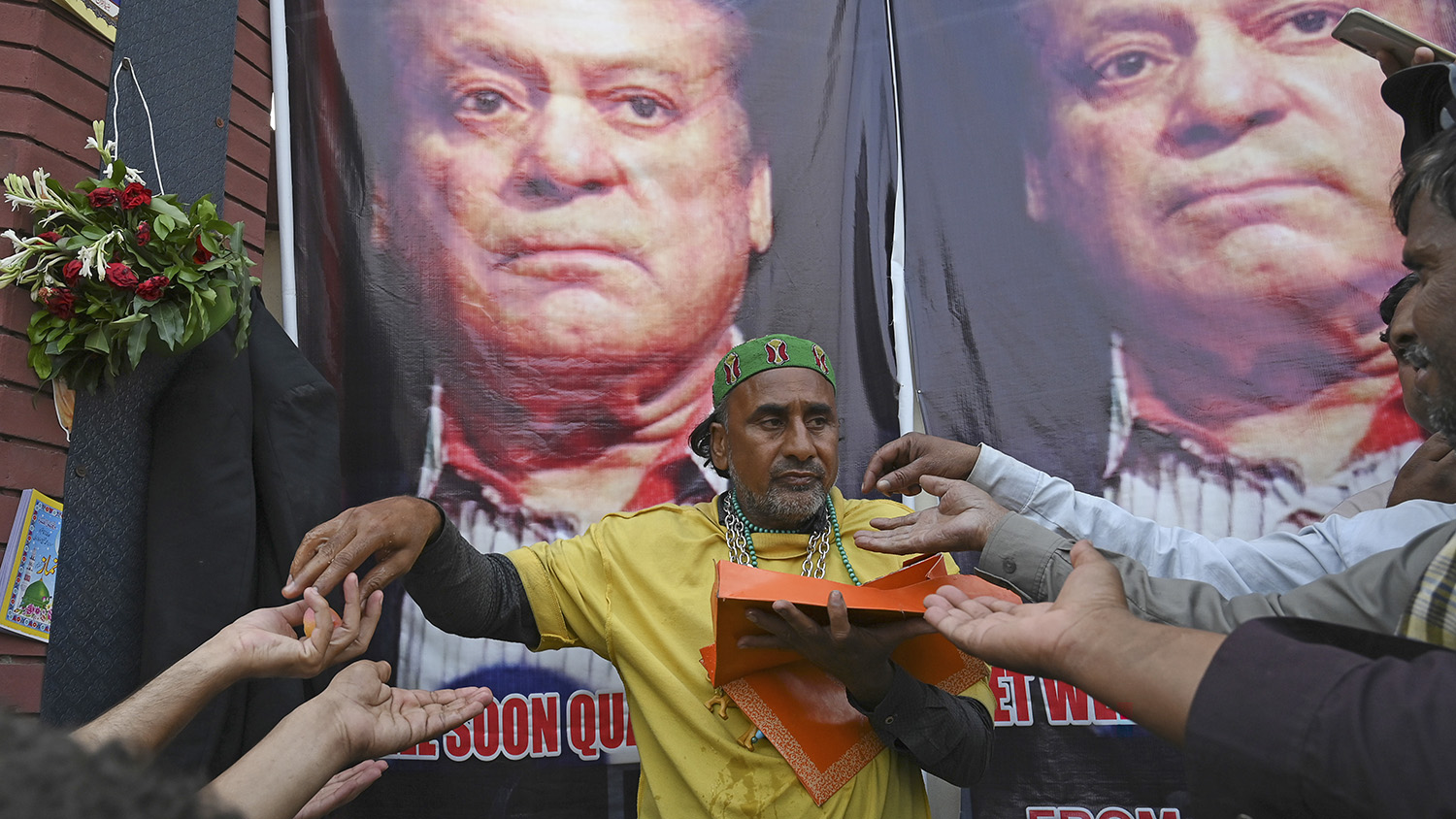 A supporter of Pakistan former Prime Minister Nawaz Sharif distributes sweets after the High court bailed Sharif on medical grounds, outside a hospital, in Lahore on Oct. 25, 2019. (AFP)