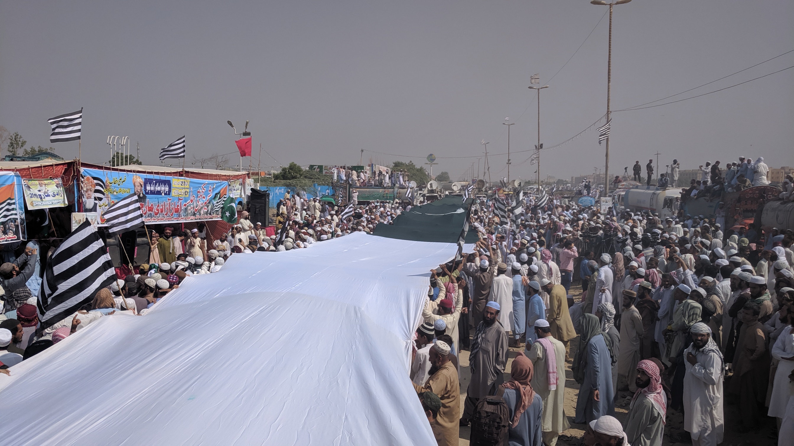 Activists of the Jamiat Ulema-e-Islam party are waving a 300 meters long national flag at party’s rally in Sohrab Goth before starting Azadi March to Islamabad on March 27, 2019 (AN Photo)