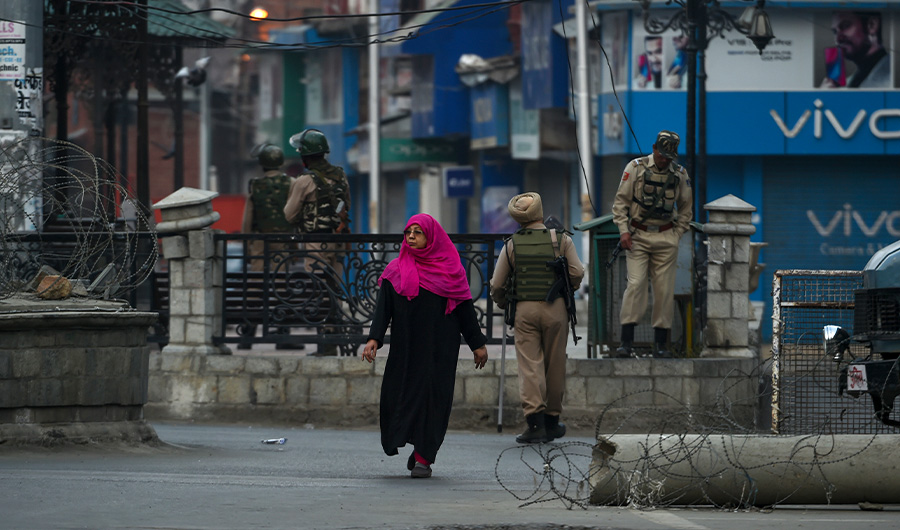 A Kashmiri woman walks as security personnel stand guard near a clock tower during a lockdown in central Srinagar on September 27, 2019. (AFP)
