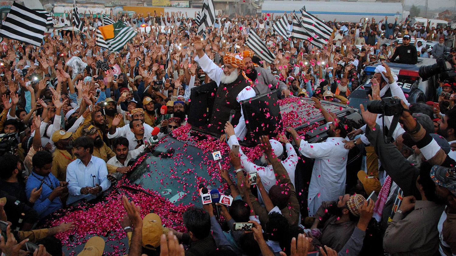 Maulana Fazlur Rehman, center, head of the Jamiat Ulema-e-Islam party, is greeted by supporters with rose-petals during an anti-government march as it arrives in Hyderabad, Pakistan, Sunday, Oct. 27, 2019. (AP)