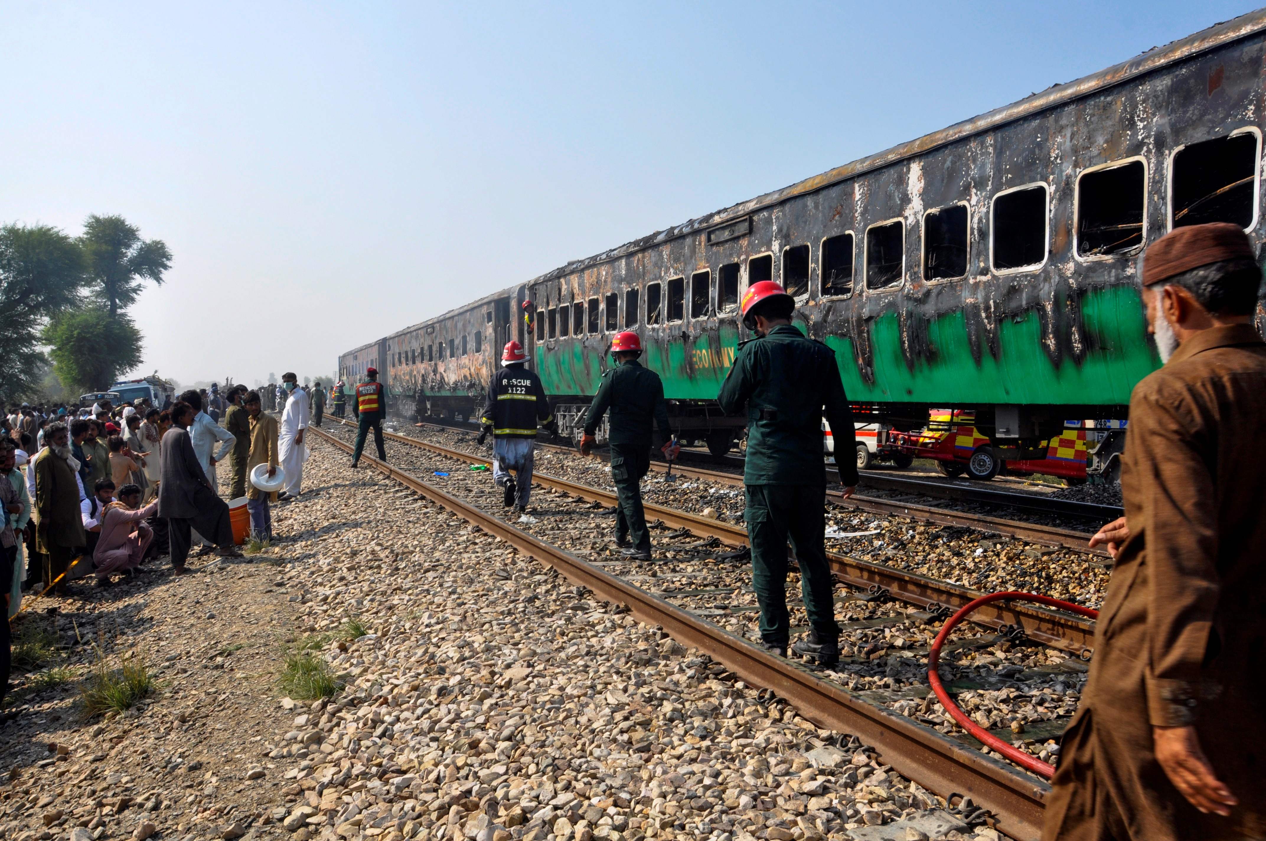 Rescue workers walk past burnt-out train carriages after a passenger train caught on fire near Rahim Yar Khan in Punjab province on October 31, 2019. At least 71 people were killed and dozens injured after cooking gas cylinders exploded on a train packed with pilgrims in Pakistan on October 31, some dying after leaping from carriages to escape the inferno, authorities said. (AFP)