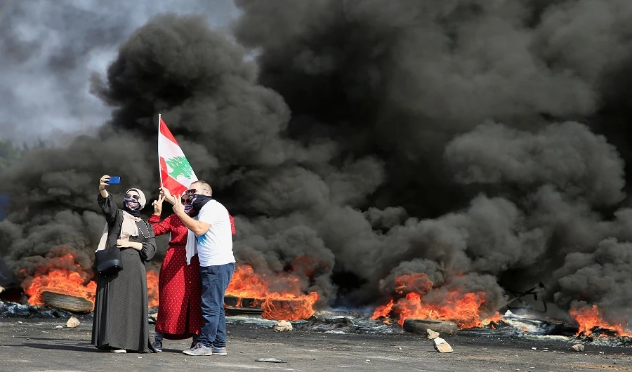Demonstrators take a selfie in front of burning tires during a protest targeting the government over an economic crisis, at Barja area blocking off a main road leading from southern Lebanon to Beirut, October 18, 2019. (REUTERS photo)