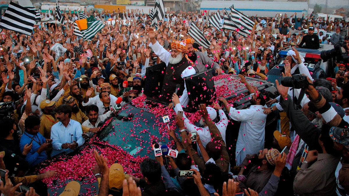 Maulana Fazlur Rehman, center, head of the Jamiat Ulema-e-Islam party, is greeted by supporters with rose-petals during an anti-government march as it arrives in Hyderabad, Pakistan, Sunday, Oct. 27, 2019. (AP)