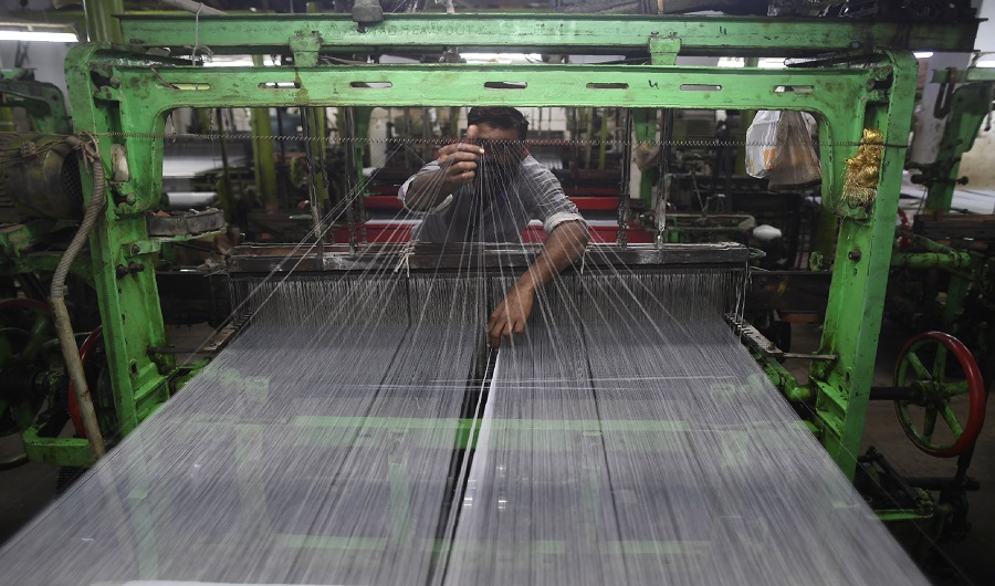 A Pakistan textile labourer fixes broken threads at a power loom in Karachi, on January 25, 2019, the financial capital and the largest industrial city of Pakistan. (AFP)
