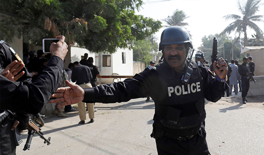 A police officer ushering people away from the Chinese consulate in Karachi on November 23rd, 2018 after the attack. (Reuters)
