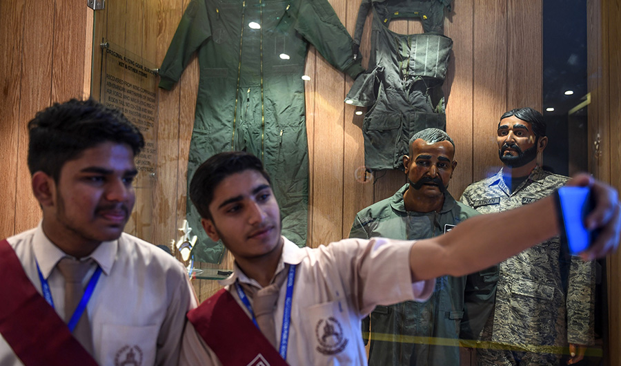Students take a selfie in front of the statue of Indian pilot Wing Commander Abhinandan Varthaman (2R) whose plane was shot down over Kashmir earlier this year, put on display at Pakistan Air Force Museum in Karachi on November 12, 2019. (AFP)