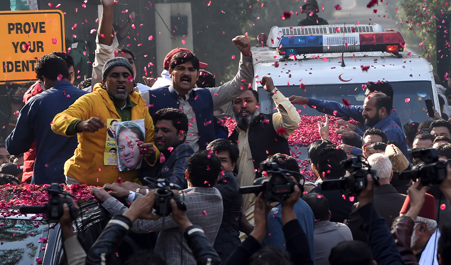 Supporters of Pakistan Muslim League Nawaz (PML-N) gather around a vehicle, covered with rose petals, carrying the ailing former Pakistani prime minister Nawaz Sharif as he travels to Lahore airport prior to his departure for abroad for medical treatment, in Lahore on November 19, 2019. (AFP)