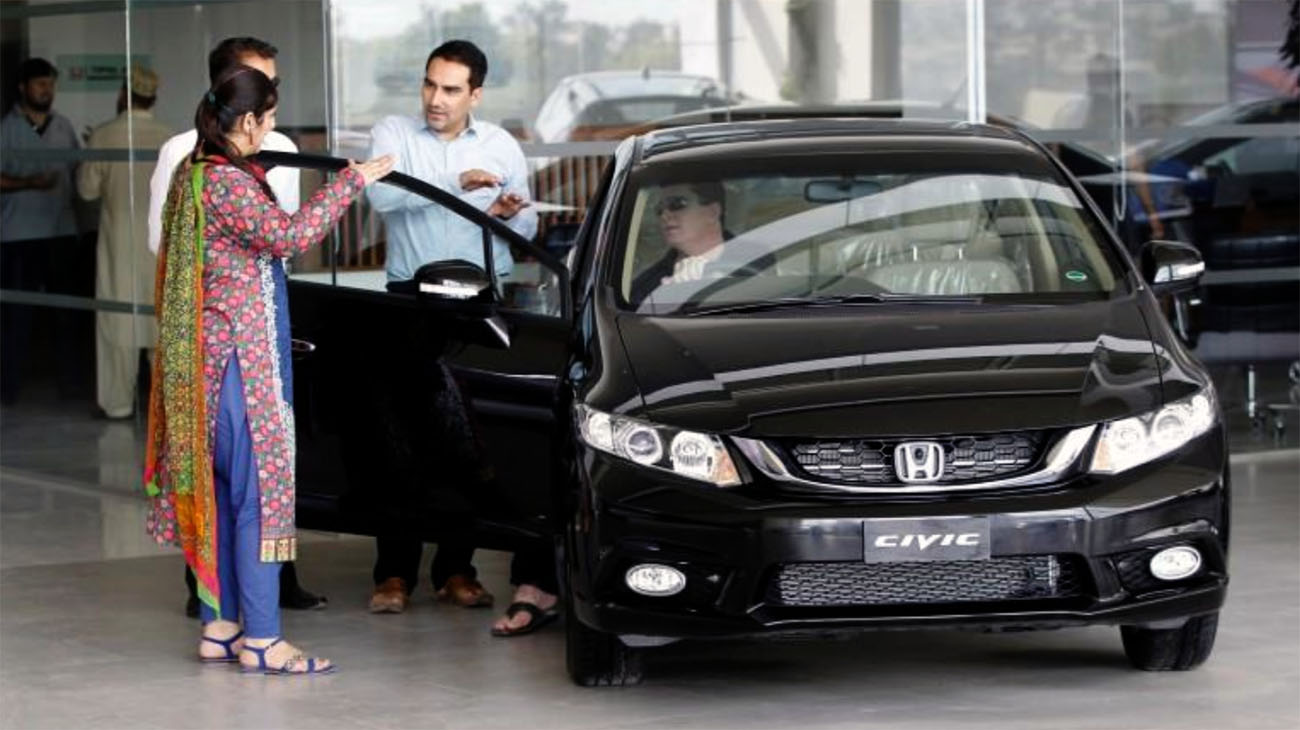 In this file photo, a customer speaks with a salesman at a car dealership in Rawalpindi on June 18, 2016. (REUTERS)