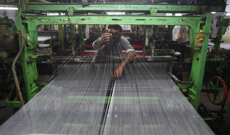 A Pakistan textile labourer fixes broken threads at a power loom in Karachi, on January 25, 2019, the financial capital and the largest industrial city of Pakistan. (AFP)