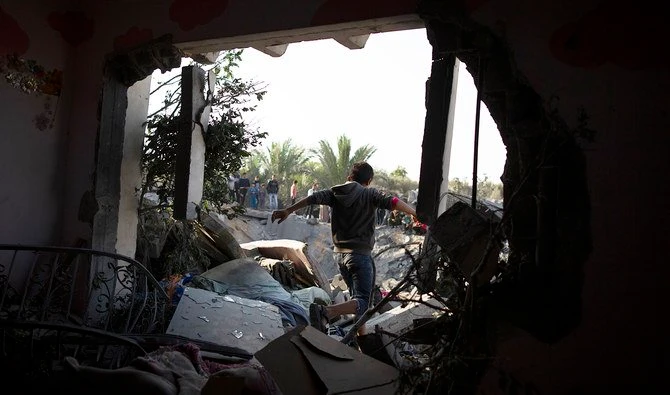 A Palestinian boy walks through a hole in a wall of a destroyed house following overnight Israeli missile strikes, in the town of Khan Younis, southern Gaza Strip. (AP)