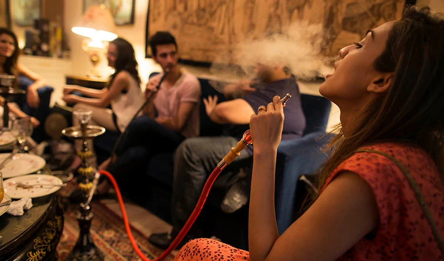 A group of girls and boys smoking smoke a water pipe, also known as a narghile, as they sit with friends at home in Islamabad May 8, 2014. (Reuters)