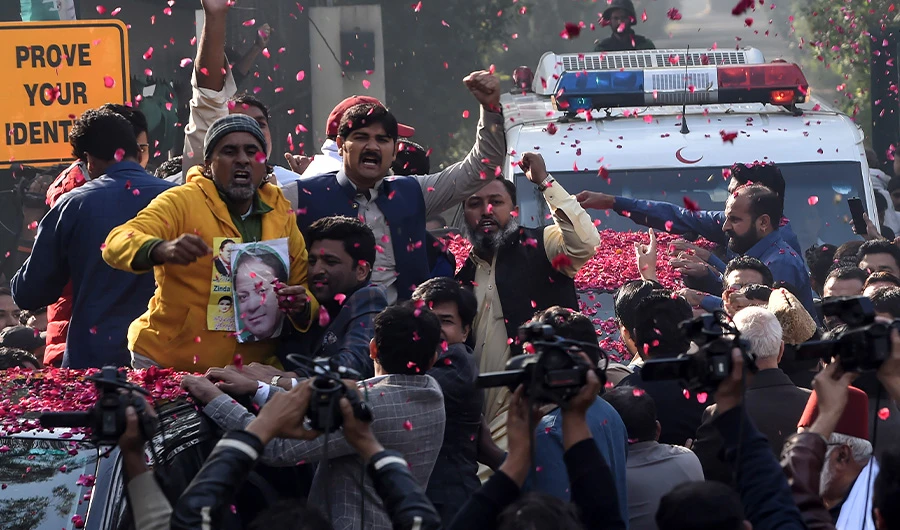 Supporters of Pakistan Muslim League Nawaz (PML-N) gather around a vehicle, covered with rose petals, carrying the ailing former Pakistani prime minister Nawaz Sharif as he travels to Lahore airport prior to his departure for abroad for medical treatment, in Lahore on November 19, 2019. (AFP)