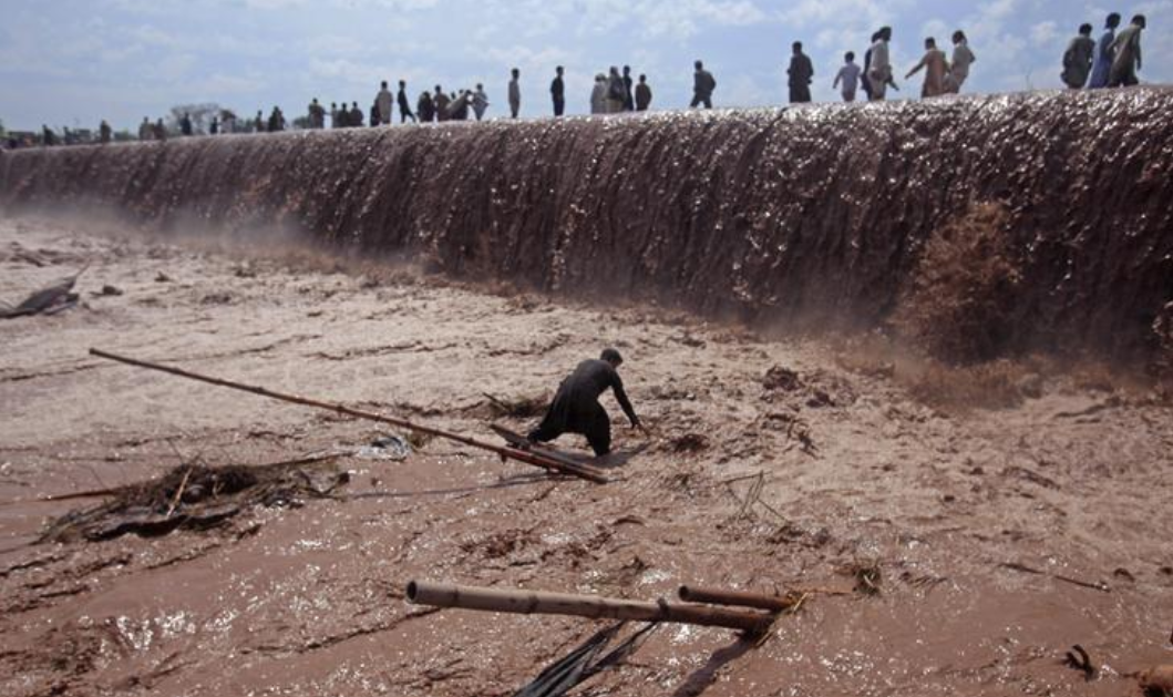 A shopkeeper tries to save belongings as residents use a bridge covered with floodwater after heavy rain in Nowshera District on the outskirts of Peshawar, Pakistan April 4, 2016. (REUTERS/ File Photo)