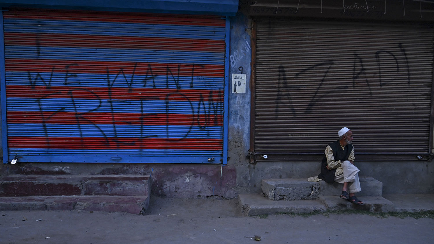 In this file photo, a Kashmiri man sits in front of closed shops during a lockdown at Anchar Soura in Srinagar on Sept. 26, 2019. (AFP)