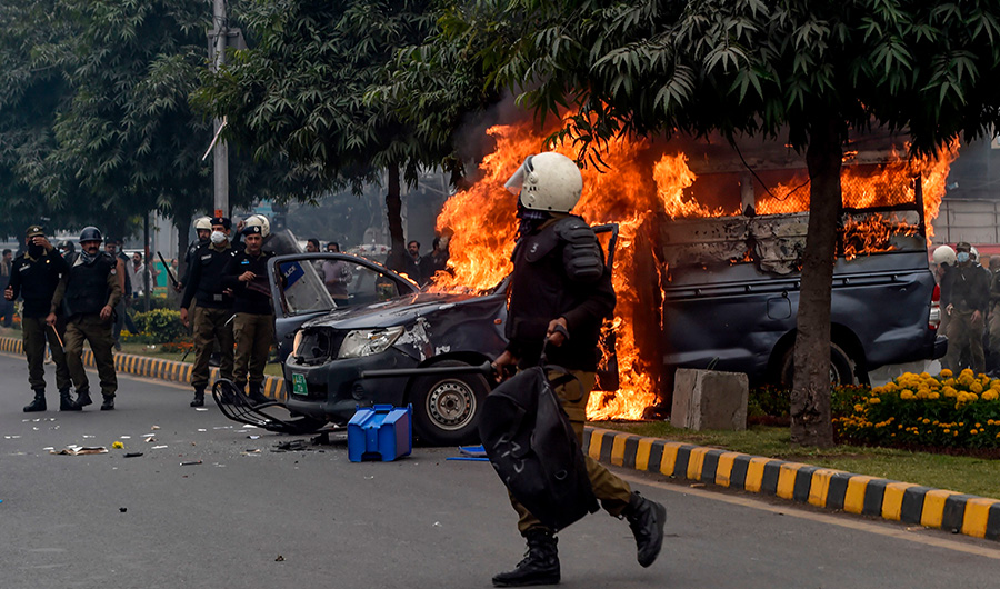 Policemen gather beside a burning police vehicle following a clash between lawyers and doctors at Punjab Institute of Cardiology (PIC) in Lahore, Dec. 11, 2019. (AFP)