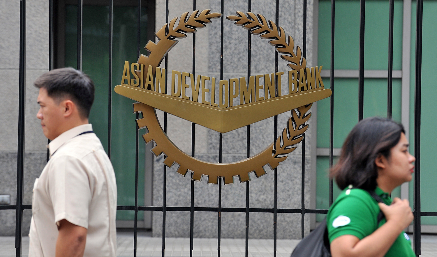 In this file photo, pedestrians walk past a logo of the Asian Development Bank (ADB) displayed outside its headquarters in Manila on Sept. 2, 2010. (AFP)
