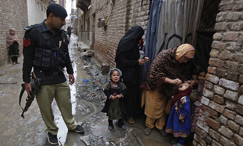A Pakistani health worker gives polio vaccine to a child escorted by a policeman in Peshawar on Feb 16, 2015. (AP/ File)