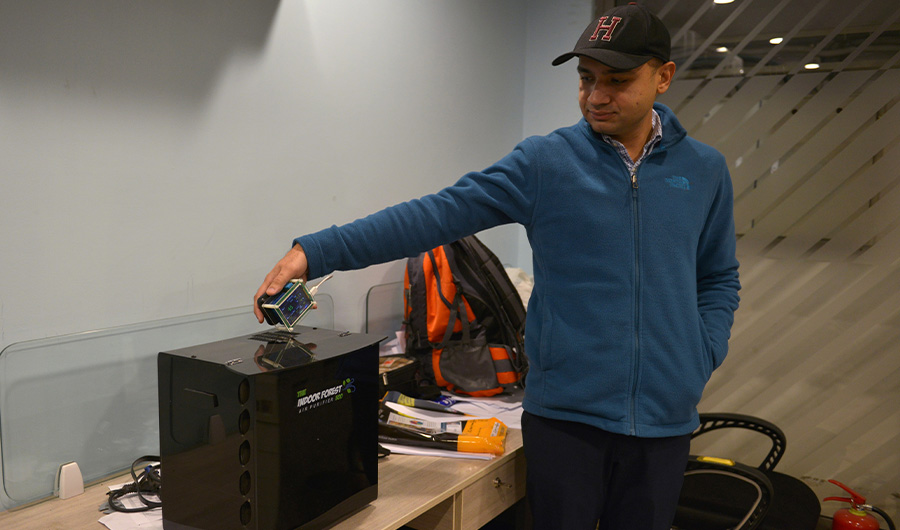 In this picture taken on December 6, 2019, inventor Hasan Zaidi checks the air quality next to his new air purifier device at the office of a customer in Lahore. (AFP)