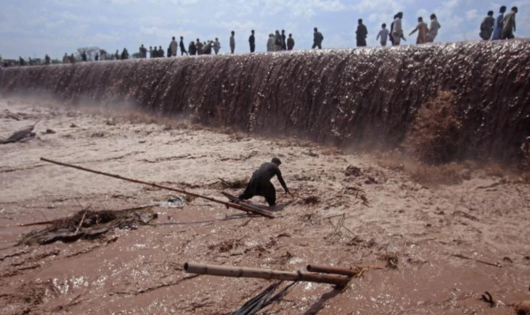 A shopkeeper tries to save belongings as residents use a bridge covered with floodwater after heavy rain in Nowshera District on the outskirts of Peshawar, Pakistan April 4, 2016. (REUTERS/ File Photo)