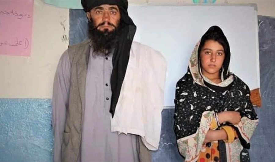 Mia Khan and his daughter Rozai pose for an undated photo inside the Nooranya School in southeastern Paktika province of Afghanistan. Khan travels 12 km daily on his motorcycle to take his daughter to school every day. (Photo courtesy: social media)