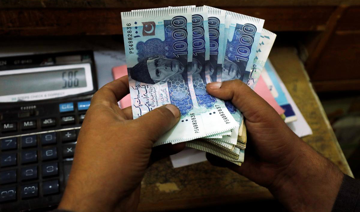 In this file photo, a trader counts Pakistani rupee notes at a currency exchange booth in Peshawar on Dec. 3, 2018. (REUTERS)