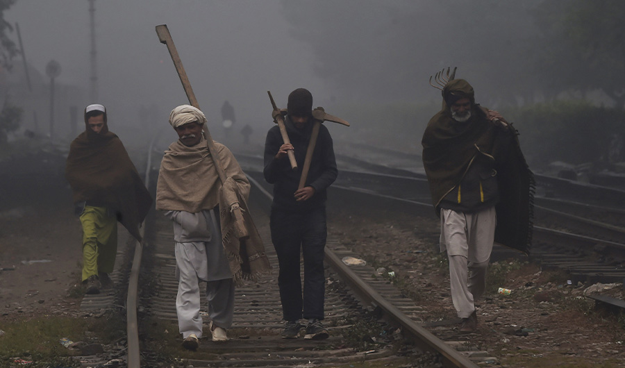 Labourers walk on a railway track during a cold and foggy morning in Lahore on January 8, 2020. (AFP)
