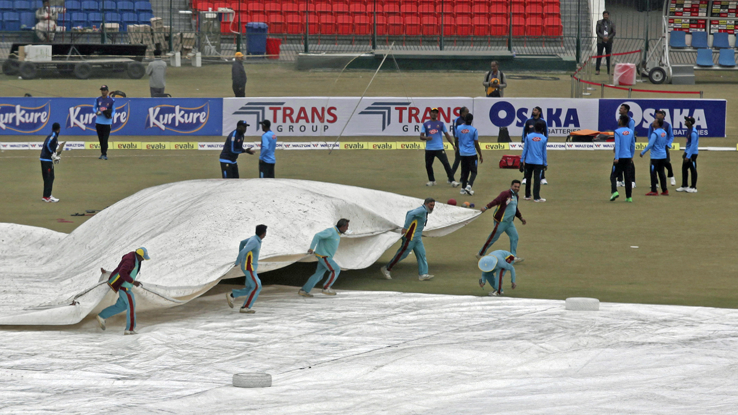 Ground staff cover a pitch during a light rain at Gaddafi stadium, in Lahore on Jan. 27, 2020. (AP)