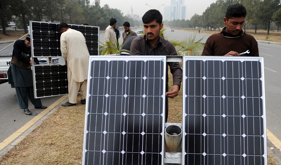 Pakistani workers prepare solar energy light panels on a road divider in Islamabad on February 2, 2014. (AFP)
