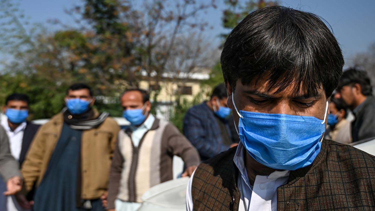 Drivers who work for a Pakistan-based Chinese company look on as they wear protective facemasks before their temperature's check in Islamabad on Jan. 30, 2020, after instructions from Pakistani authorities to take preventive measures against the coronavirus. (AFP)