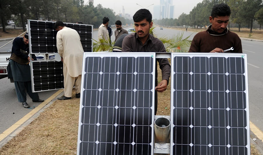 Pakistani workers prepare solar energy light panels on a road divider in Islamabad on February 2, 2014. (AFP)