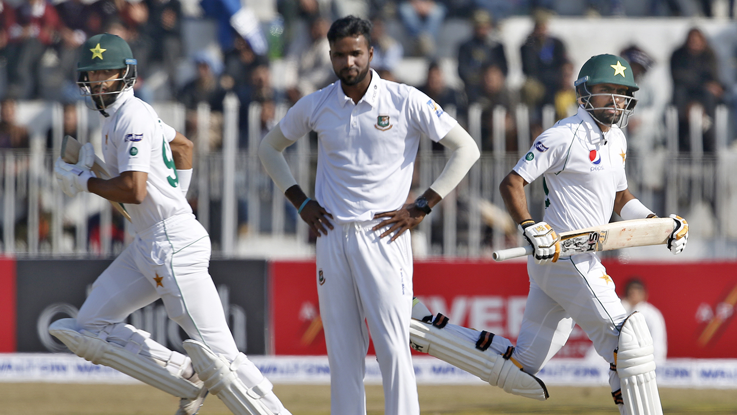 Pakistani batsmen Shan Masood, left, and Babar Azam, right, run between the wickets as Bangladesh pacer Ebadot Hossain looks on during their second day of the first test cricket match at Rawalpindi cricket stadium in Rawalpindi on Feb. 8, 2020. (AP)