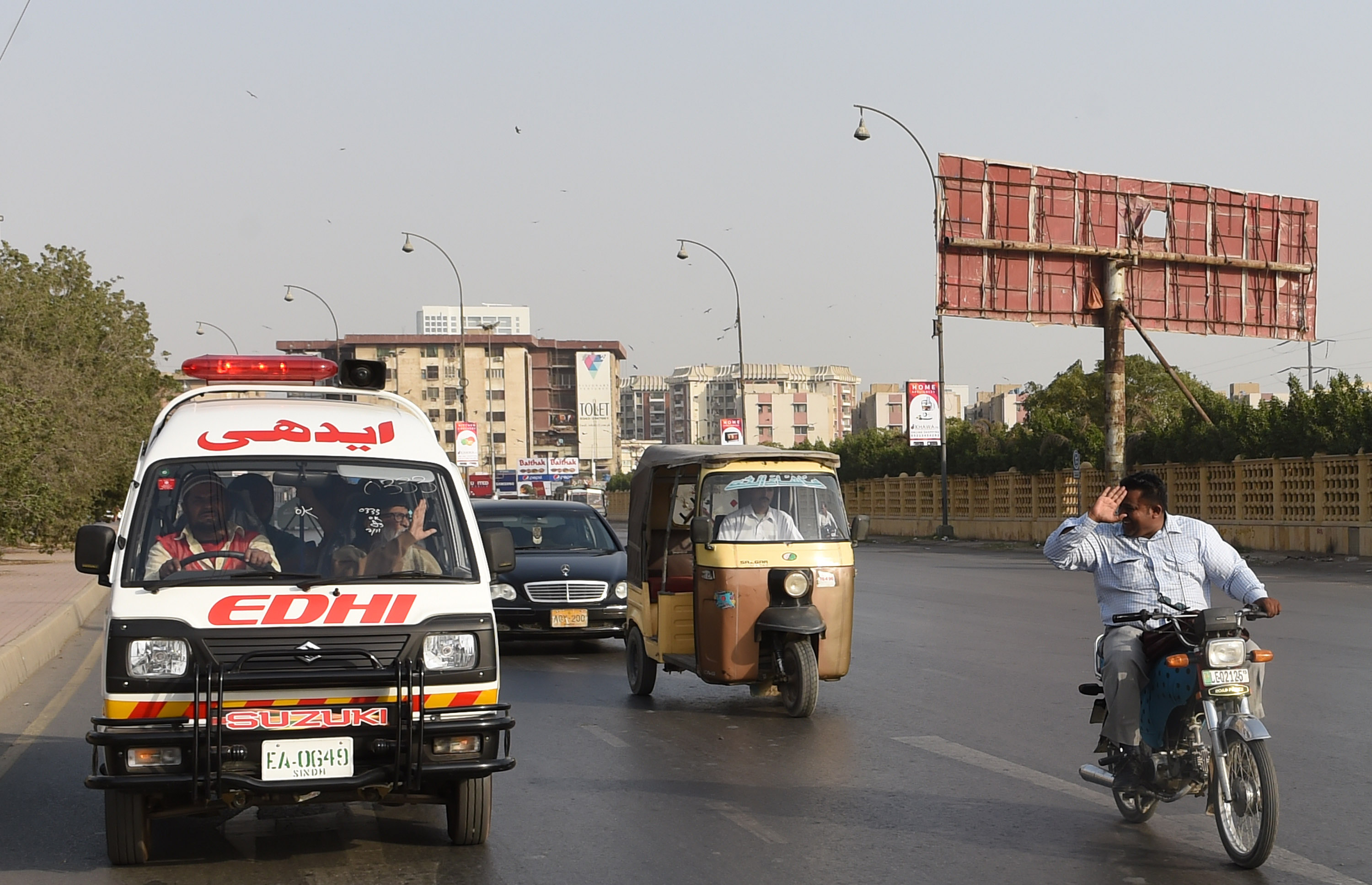 In this photograph taken on February 15, 2016, a Pakistani motorcyclist (R) pays his respects to Abdul Sattar Edhi (2nd L), the head of Edhi Foundation, as he travels to his his office in the port city of Karachi. (AFP)