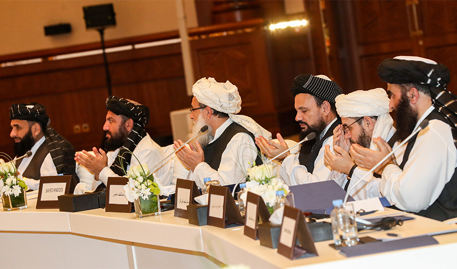 Members of the Taliban attending the second day of the Intra Afghan Dialogue talks raise their hands as they recite a prayer while seated during the talks in the Qatari capital Doha on July 8, 2019. (AFP)
